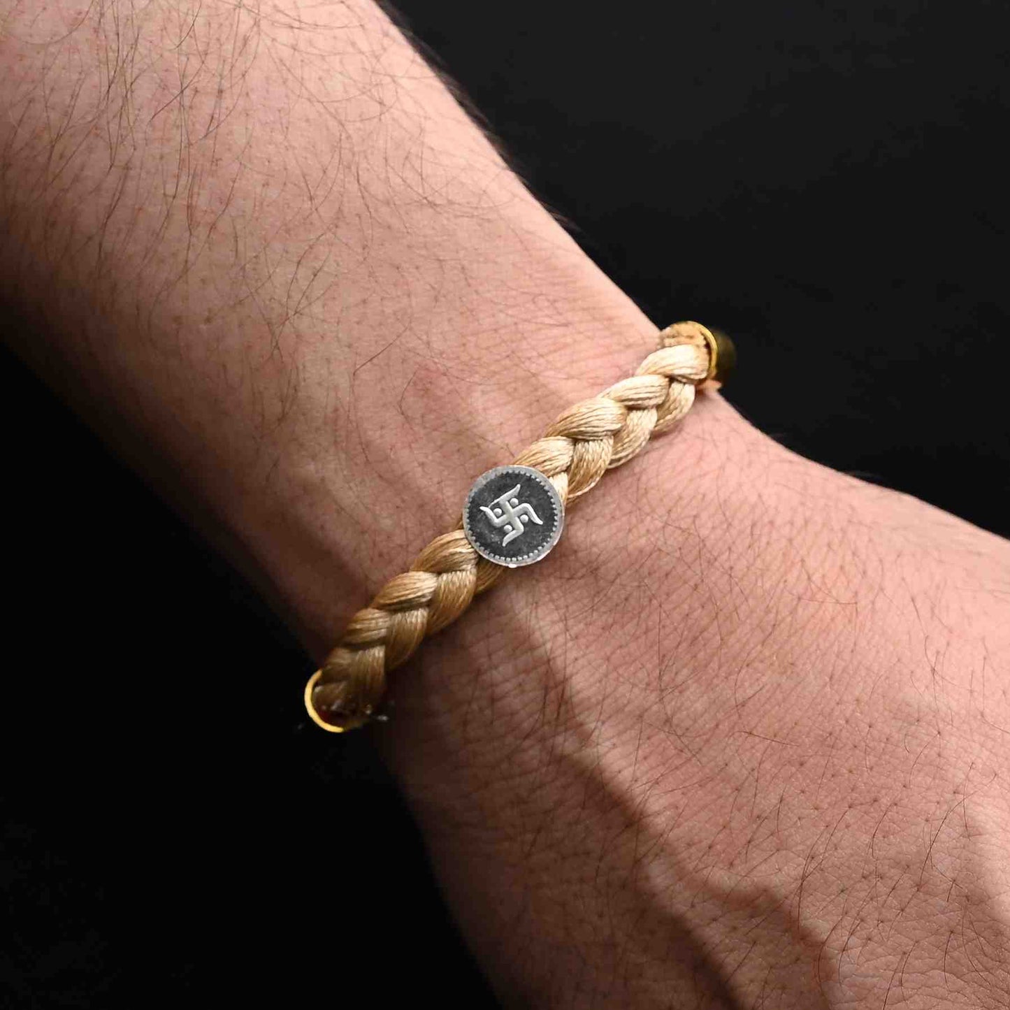 Elegant Rakhi with a silver Swastik and cream tangle Moli accents, ideal for boys.