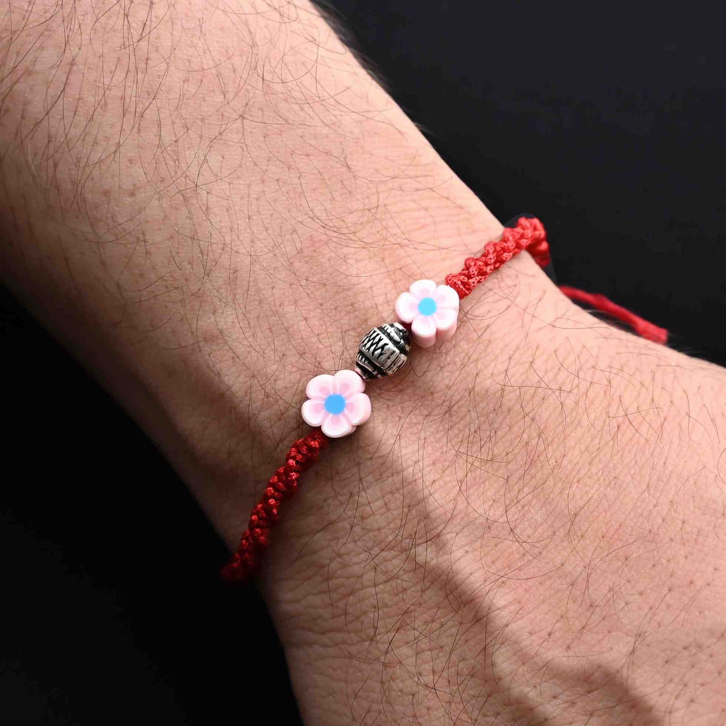 Elegant Rakhi with silver beads and delicate pink flower details, ideal for boys