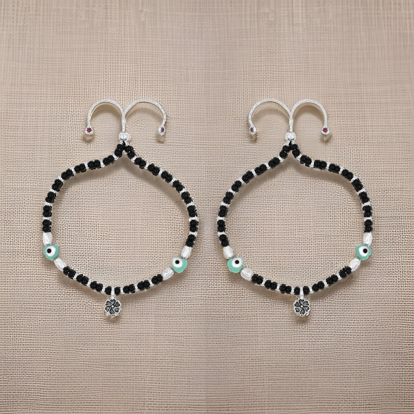 Charming silver anklet featuring a protective evil eye, black beads, and floral accents for a stylish and unique design