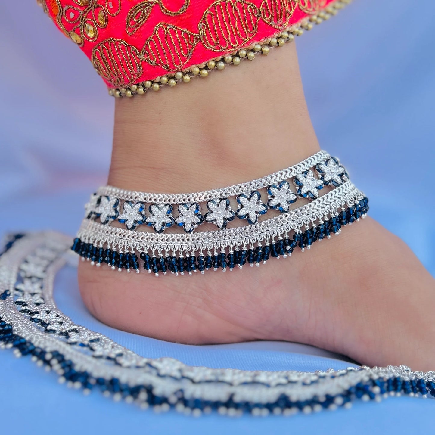 Elegant silver payal featuring blue stones and flowers.
