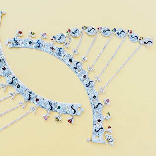 Elegant silver payal with intricate pag phool design and light peacock bud accents.