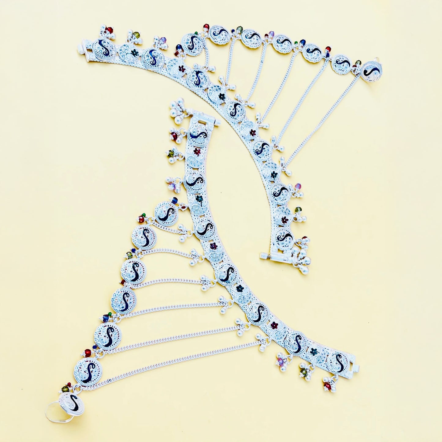 Silver payal adorned with pag phool motif and delicate light peacock bud details.