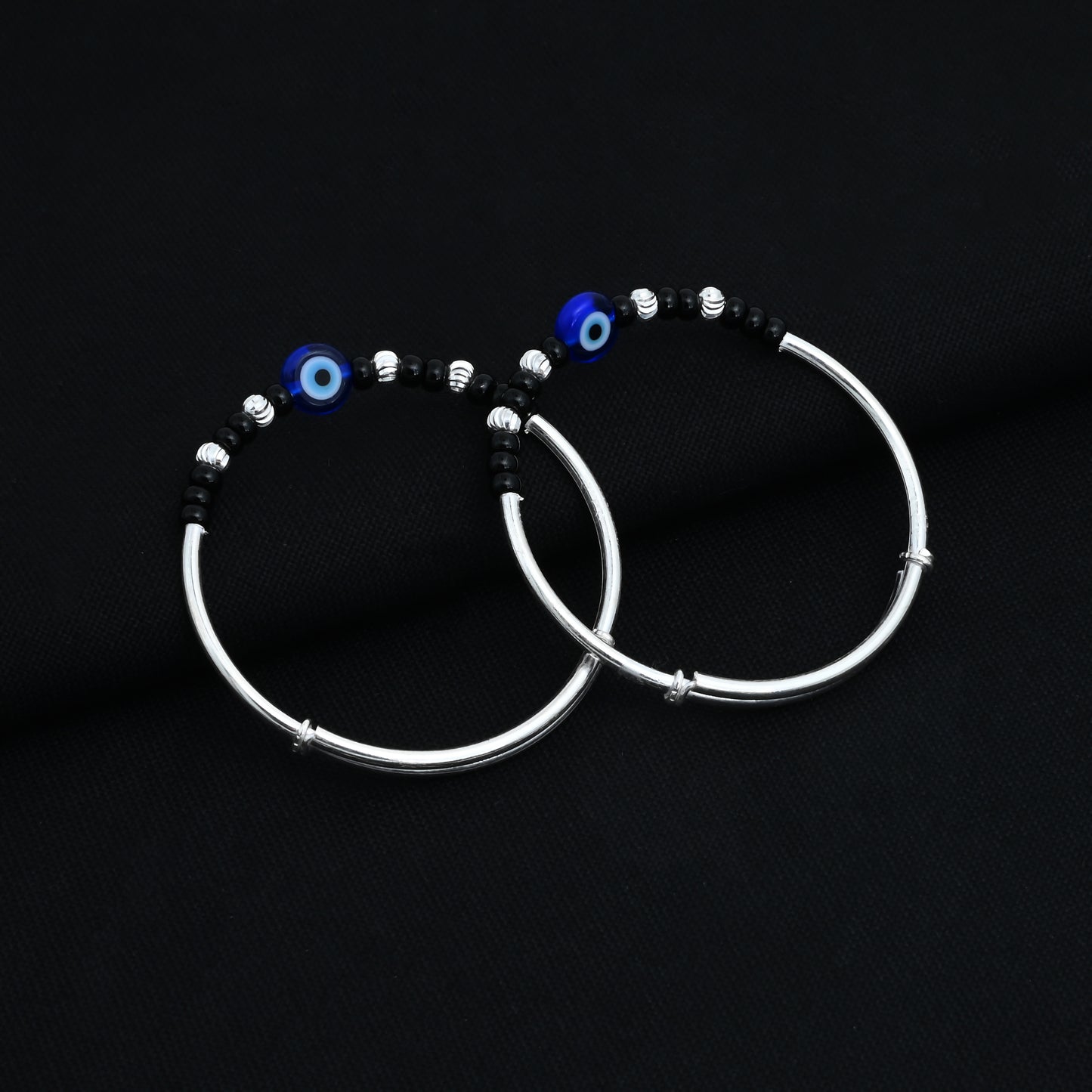 Charming silver kada payal for babies, adorned with a blue evil eye and black and silver beads.