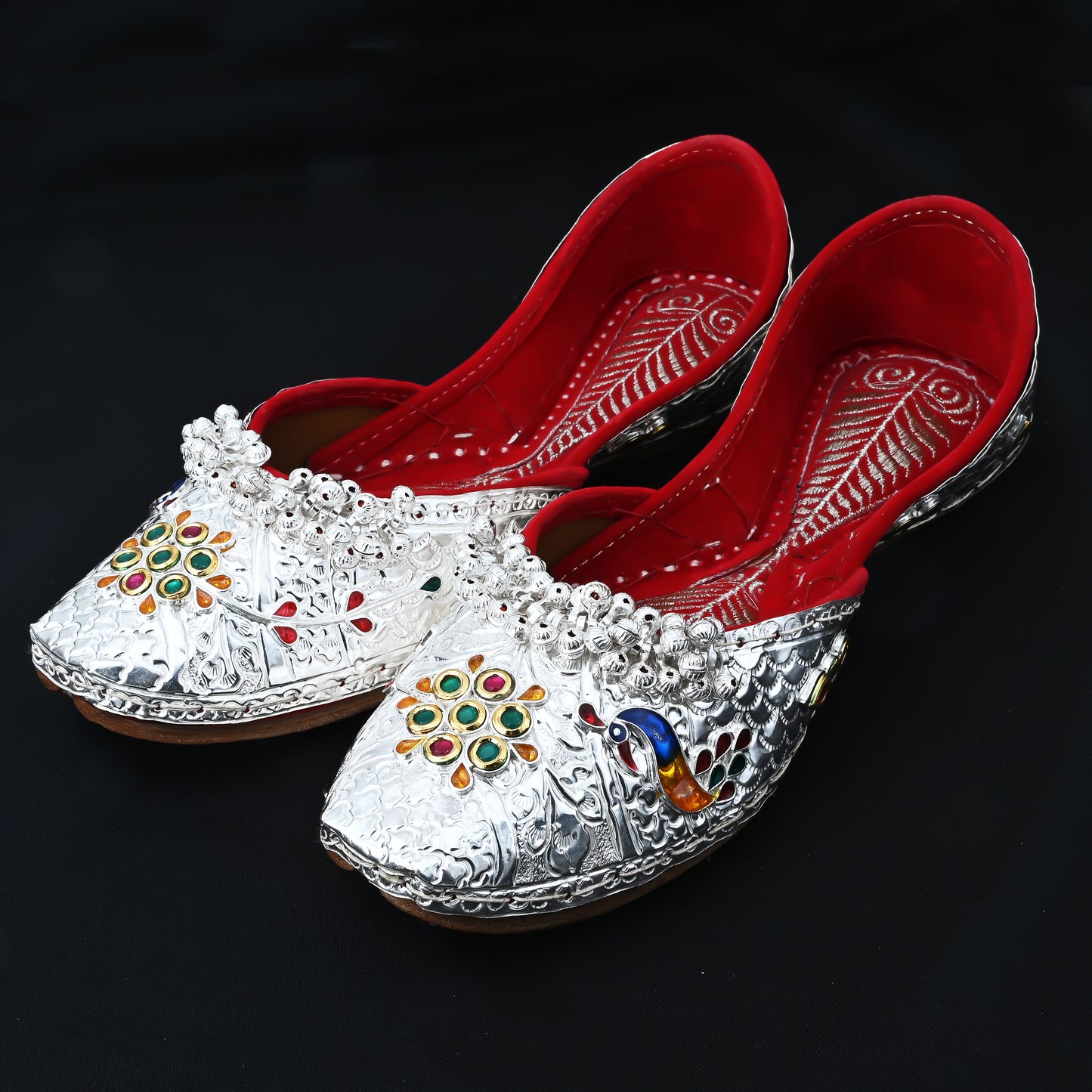 Silver jutti with intricate design and multicolored stone accents