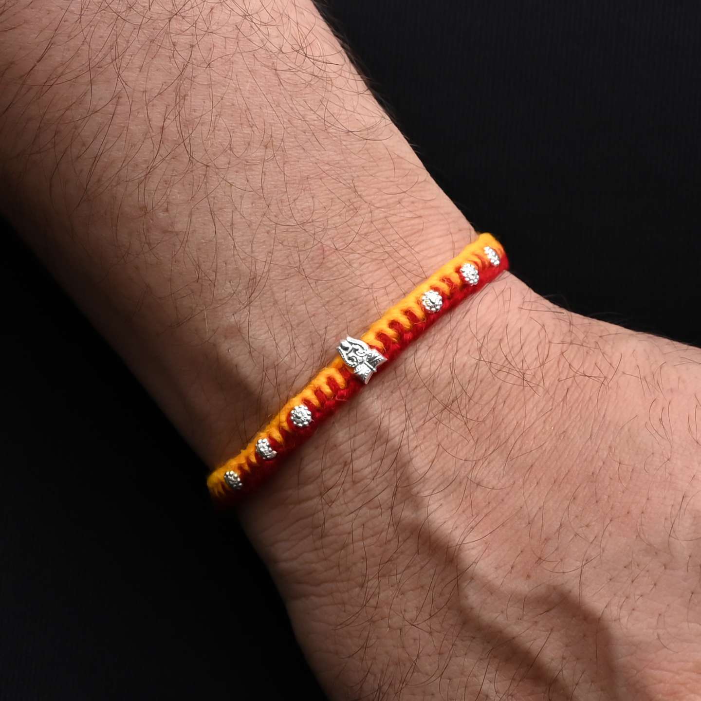 Elegant Rakhi with a silver Trishul and floral design beads, ideal for boys
