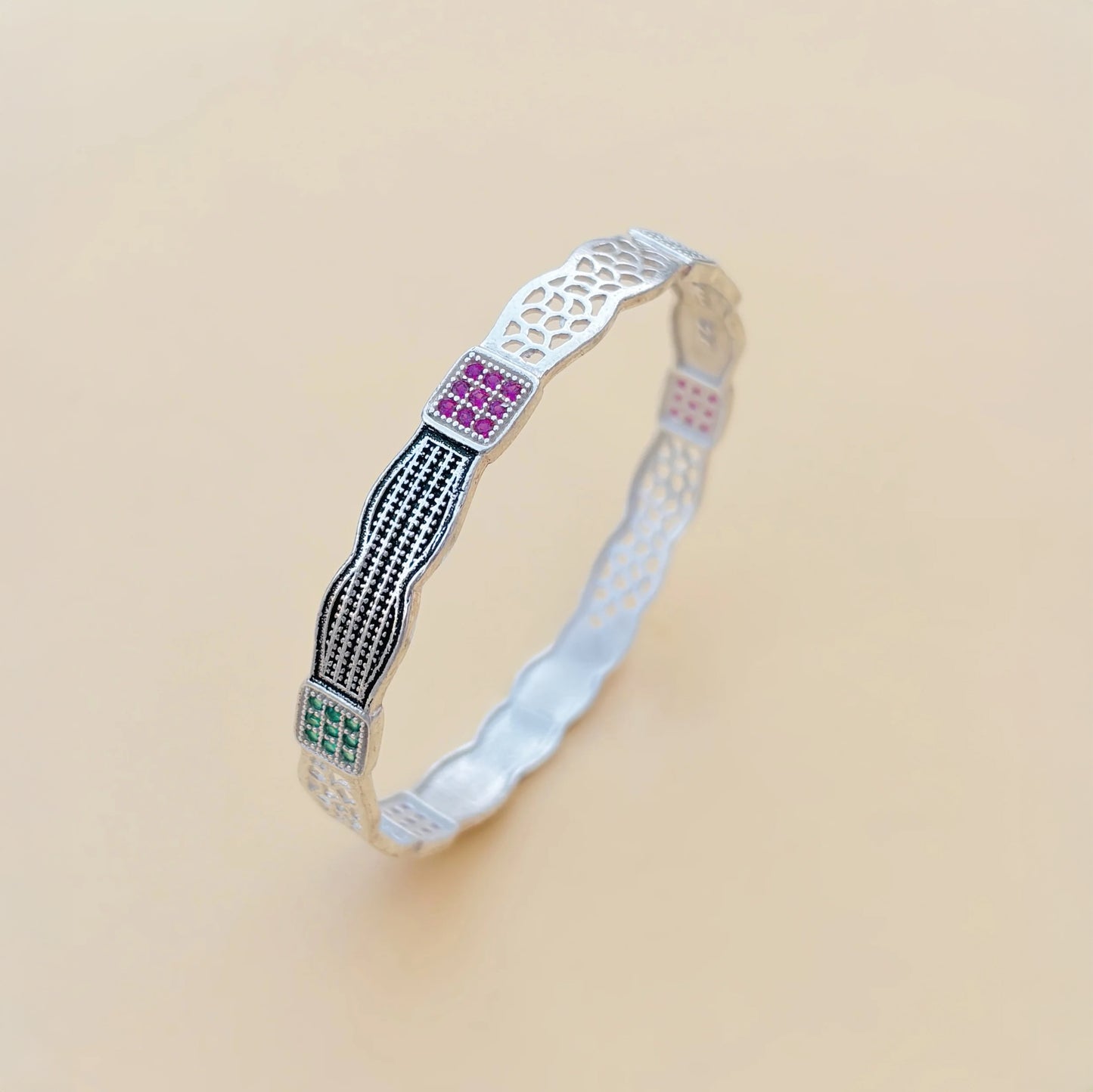 Silver kada with a stylish, unique design featuring purple and green stones.