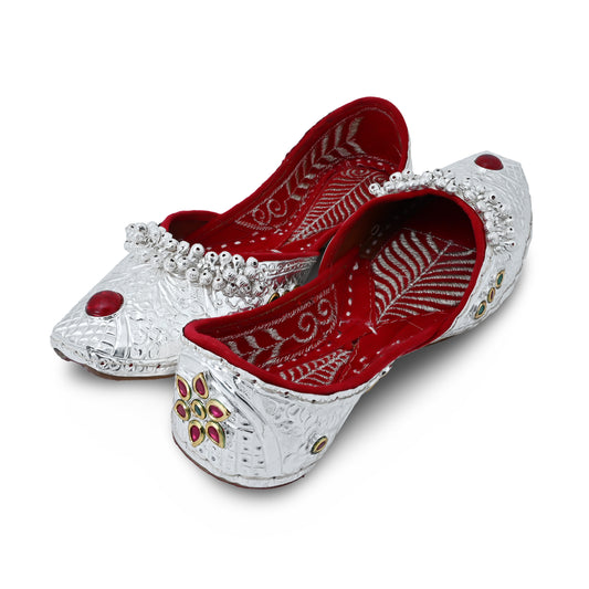 Silver jutti featuring a flower design, red stone, and ghungroo accents