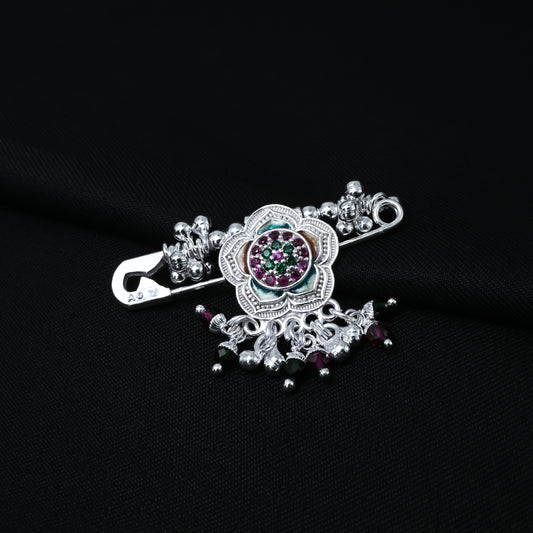 Elegant silver saree pin featuring a floral motif and multicolour stones