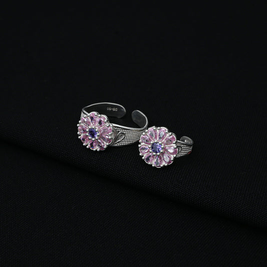 Silver toe rings featuring a floral design with pink stone accents.