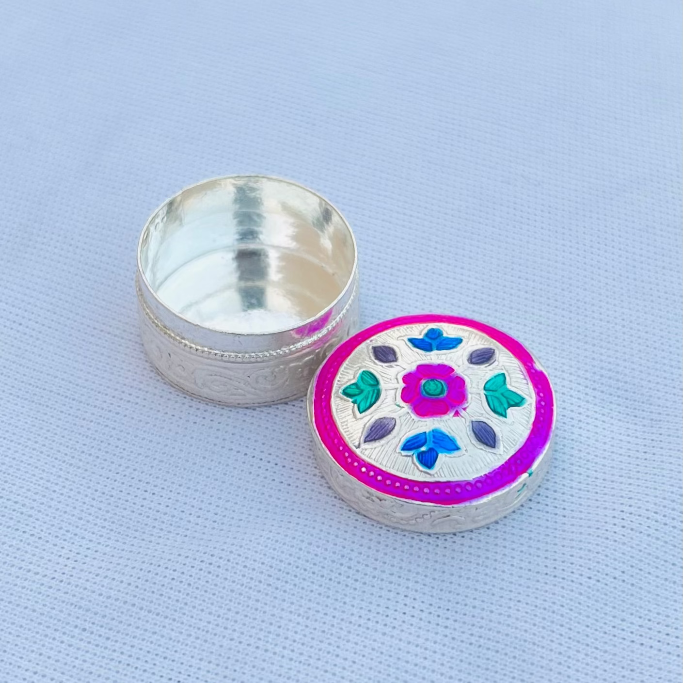 Beautiful silver sindor box adorned with pink flower and multicolor leaf accents.