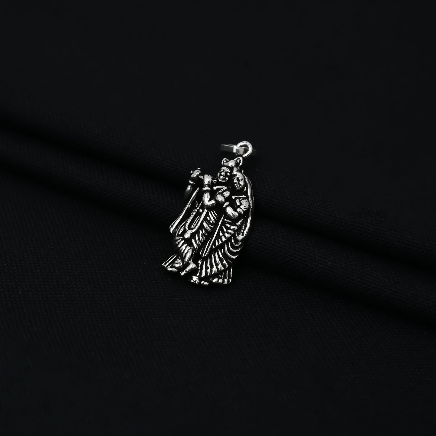 This sterling silver pendant features Radha Krishna, a beloved deity in Hinduism, playing a flute. Handcrafted with intricate detailing, this pendant showcases the skilled craftsmanship and devotion of the maker.