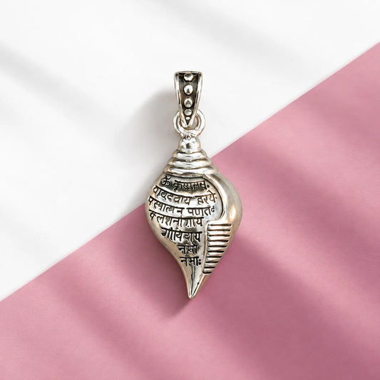 Silver Shankh pendant with engraved Sanskrit mantra and polished shell-shaped design on a pale sage green background