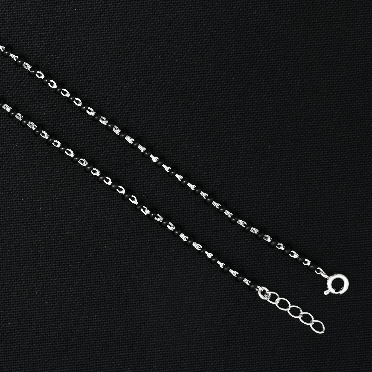 Charming silver anklet with green gems and black beads for a unique design