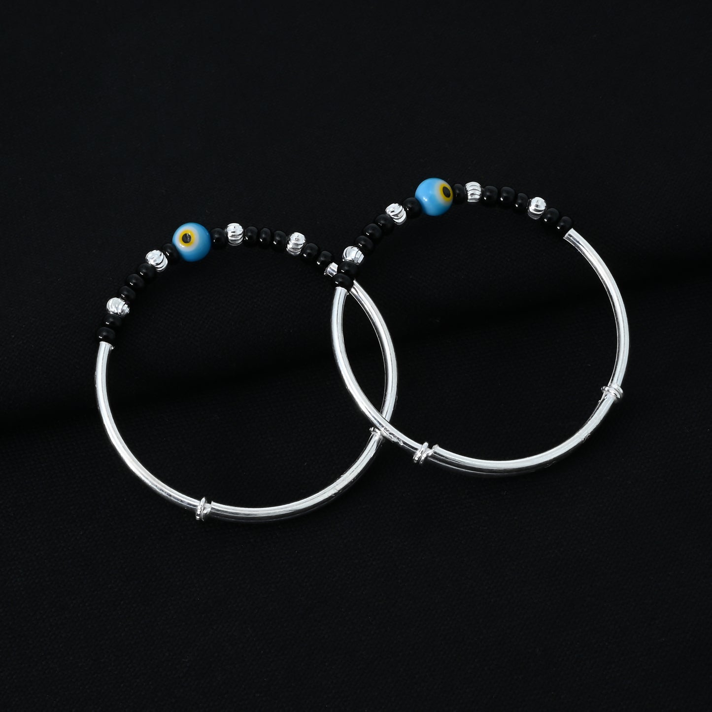 Charming silver kada payal for babies, with a protective blue and yellow evil eye and black and silver beads.