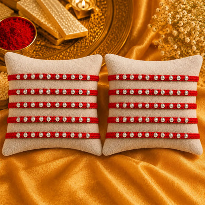Red Rakhi with silver beads displayed on a beige cushion with golden festive background