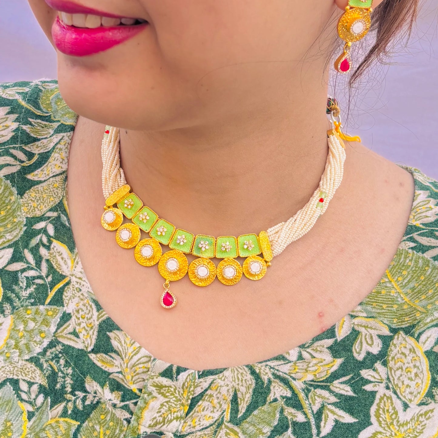 Gold polish silver necklace with intricate green buds and a vibrant red center stone.