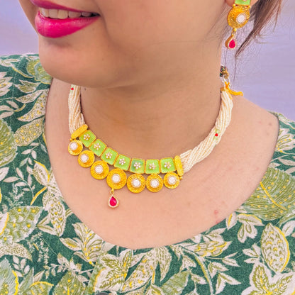 Gold polish silver necklace with intricate green buds and a vibrant red center stone.