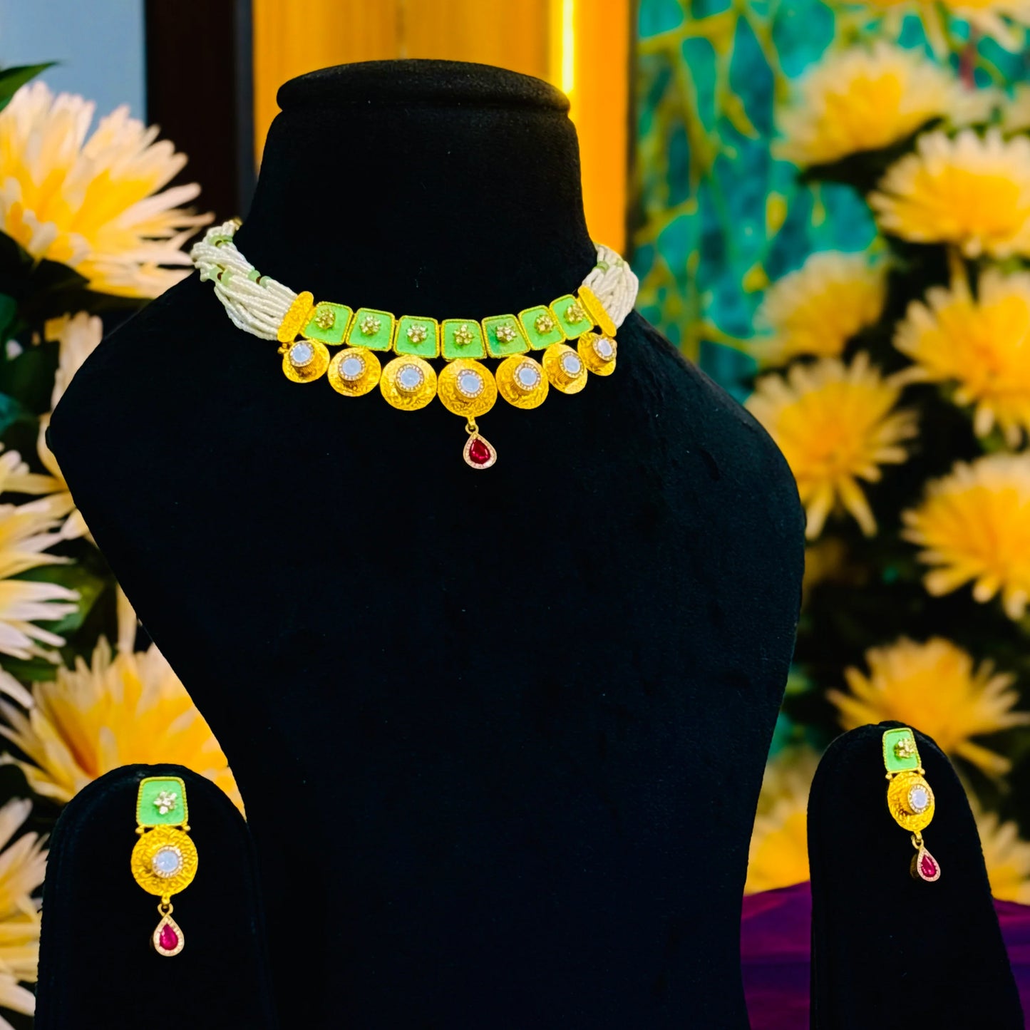 Luxurious necklace with gold polish, green buds, and a striking red centerpiece.