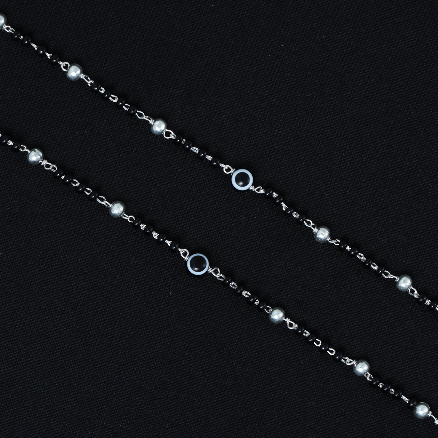 Elegant silver payal with black beads and a black evil eye symbol, perfect for modern style