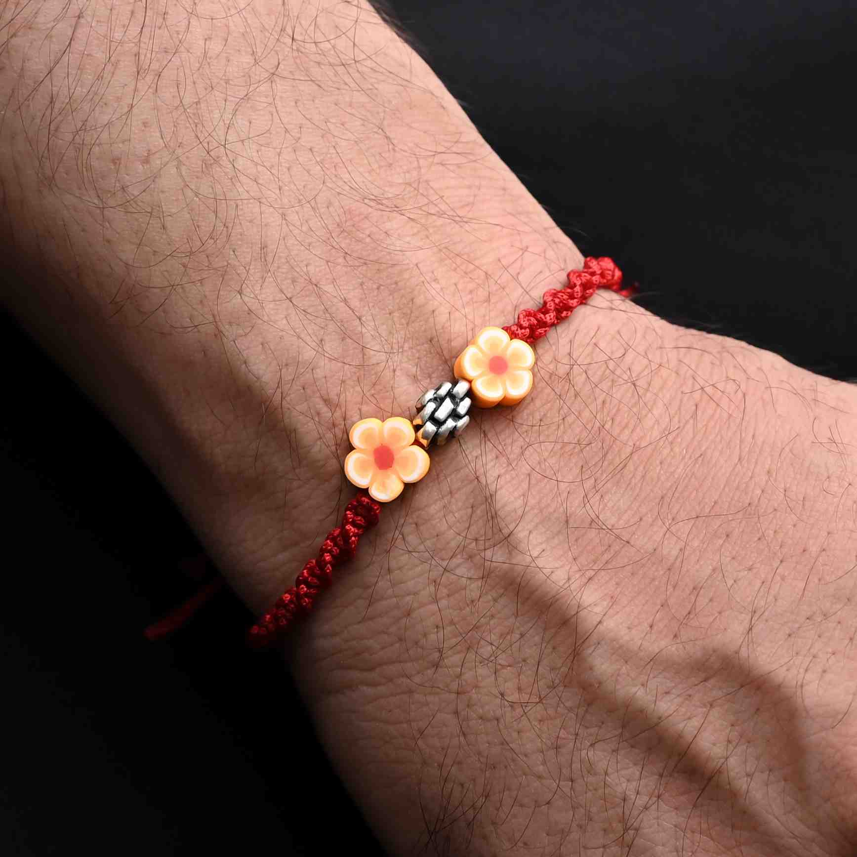 Elegant Rakhi with silver beads and orange flower accents, ideal for boys.