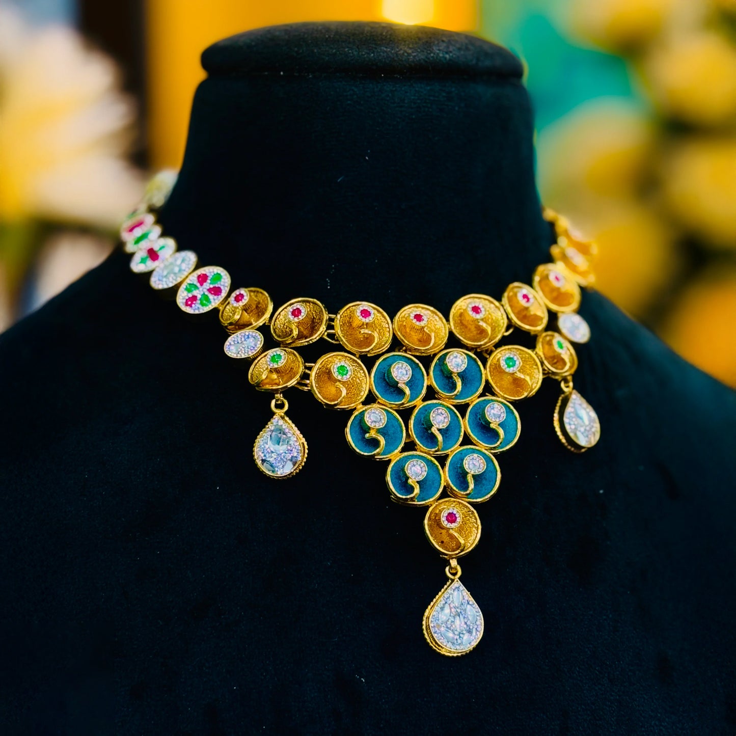 Gold polish silver necklace adorned with multicolor stones, paired with blue centerpiece earrings.