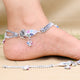 Delicate silver anklet adorned with floral motifs and gemstones.