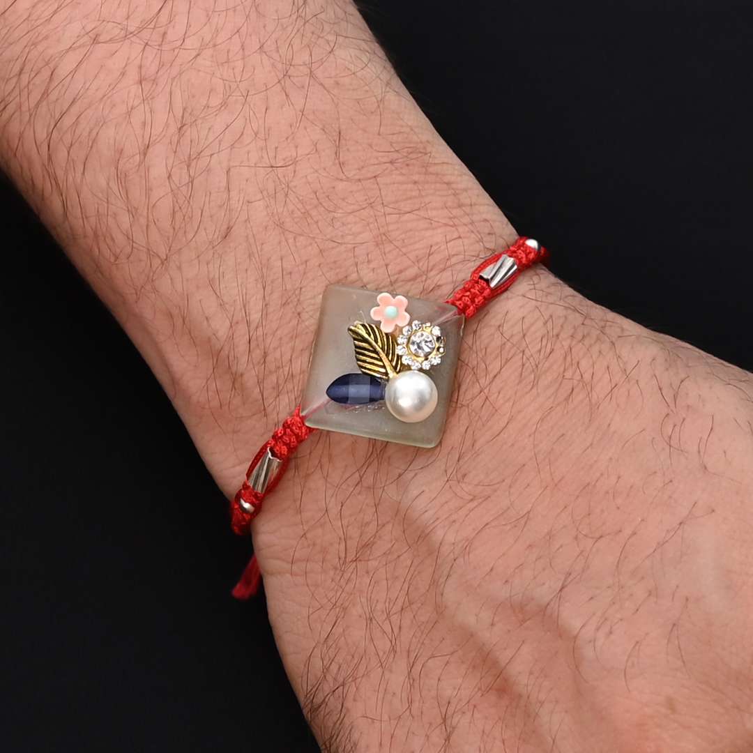Elegant Rakhi with silver flowers and pearls, ideal for boys.