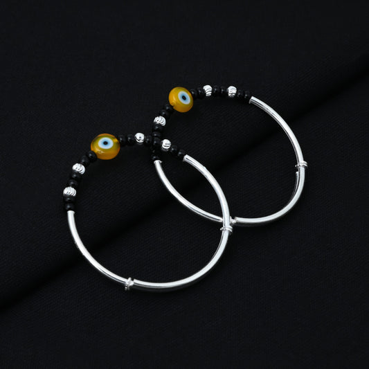 Elegant silver baby kada adorned with black beads and an evil eye charm