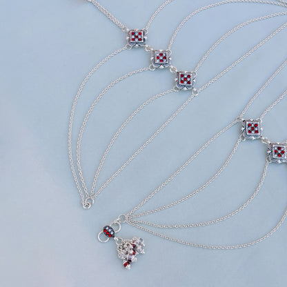 Intricate flower design silver payal adorned with colorful stones.