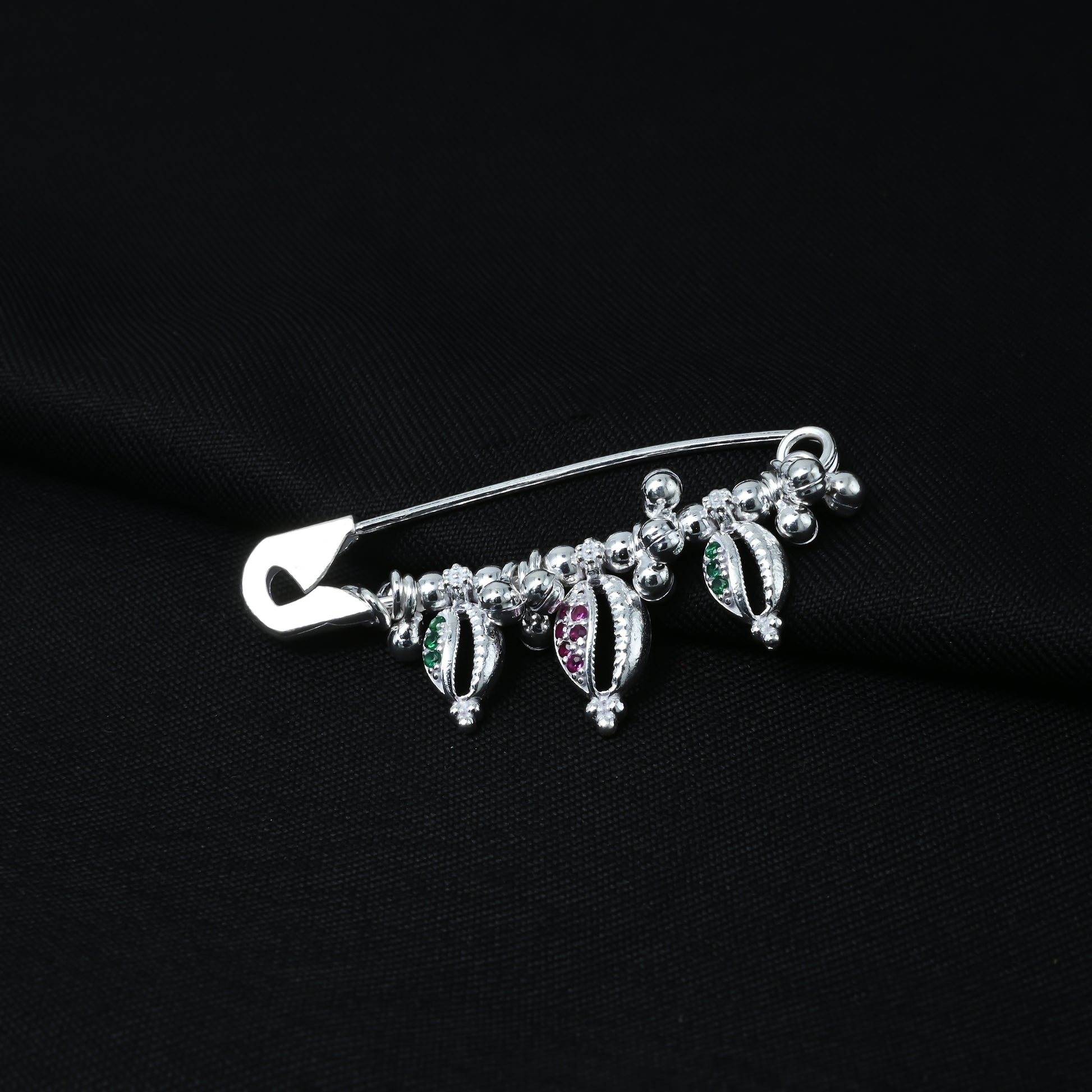 Elegant silver saree pin featuring a shell motif and green-purple stones