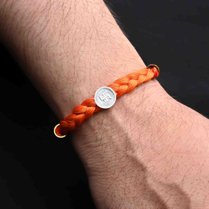 Elegant Rakhi with a silver Swastika and bold orange tangle Moli, ideal for boys.
