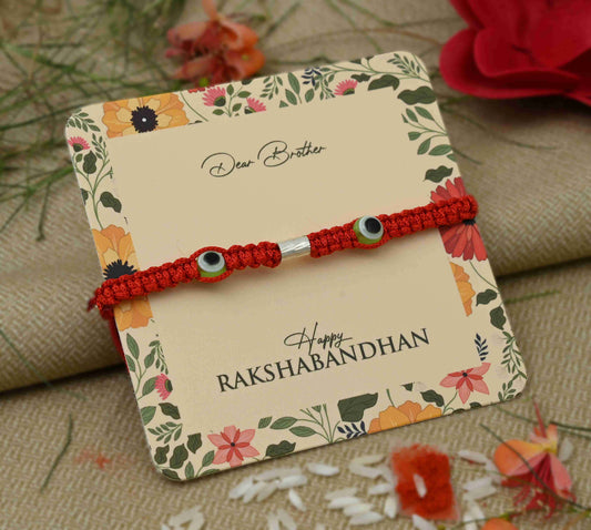 Silver Rakhi featuring two green evil eye symbols, perfect for boys