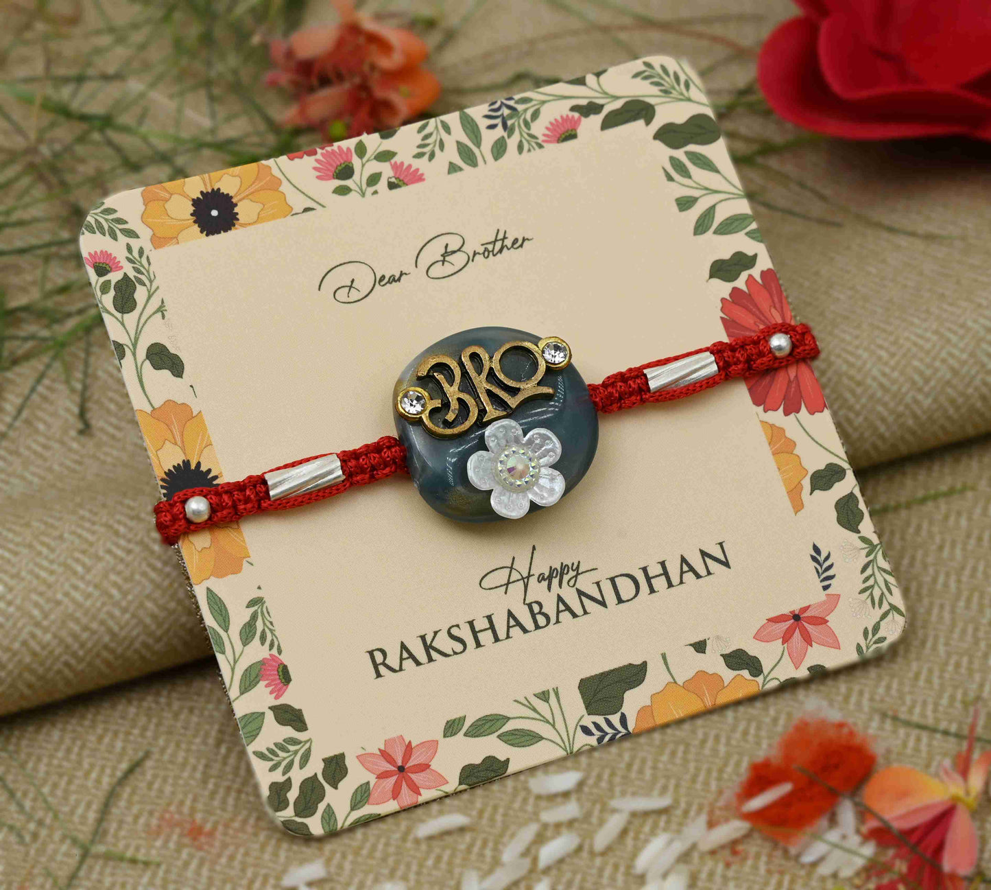 Silver center 'Bro' design on a blue background with a white flower, perfect Rakhi for boys.