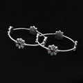 Silver kada adorned with a flower design and sparkling gemstones