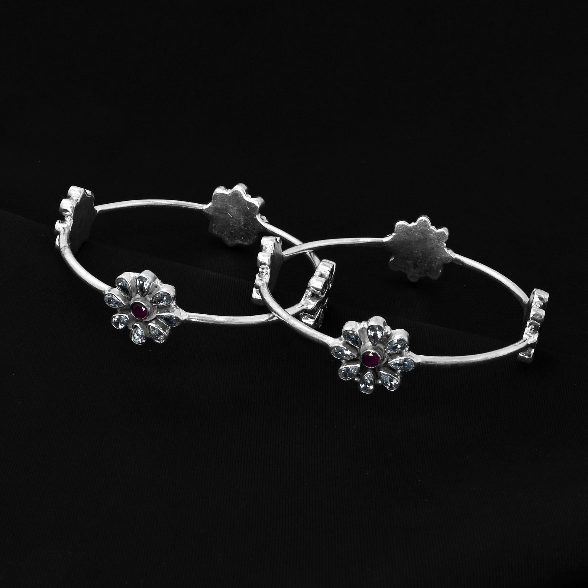 Silver kada adorned with a flower design and sparkling gemstones