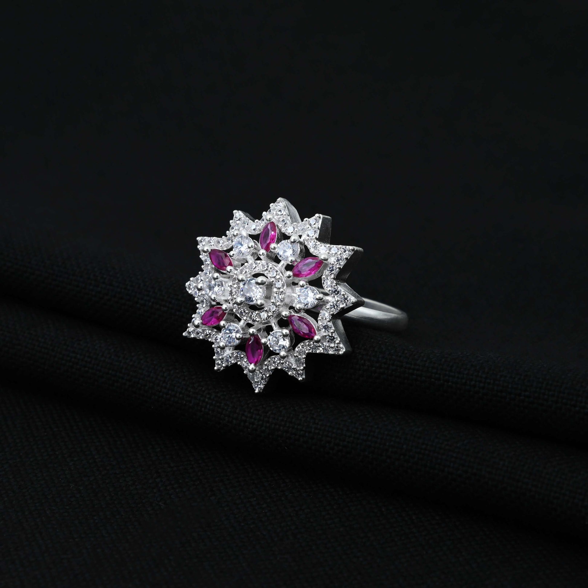 Cute silver ring with a pink gemstone at the center of a flower design for girls.