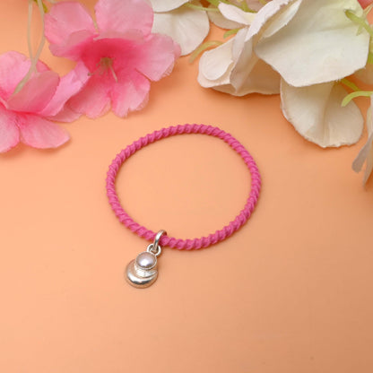 A string bracelet featuring a delicate silver charm