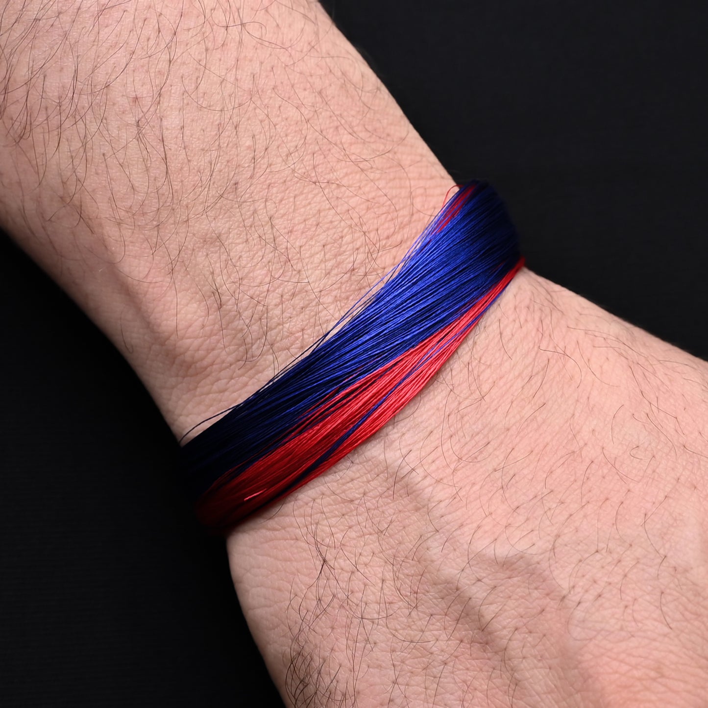 Stylish silver bracelet with a vibrant blue and red thread pattern, perfect for adding a pop of color