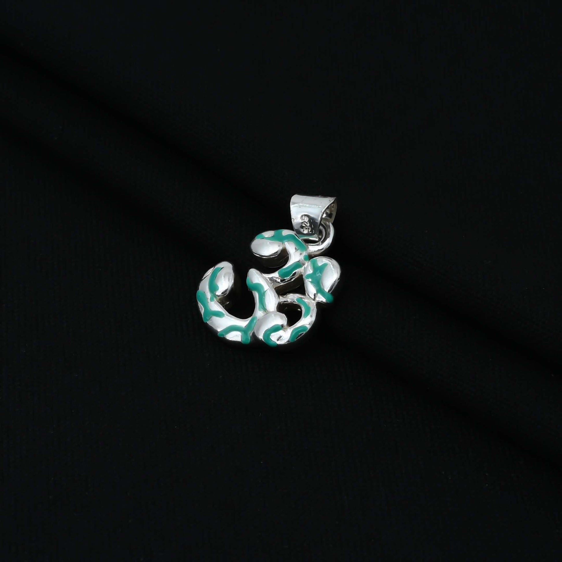 Charming sterling silver pendant with a green Om symbol and intricate lining details, ideal for girls