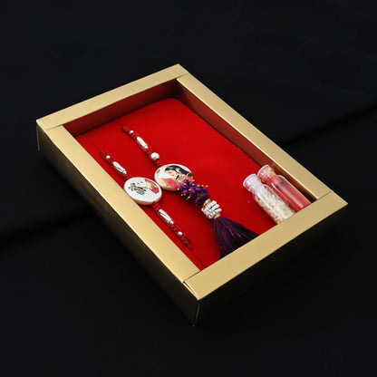 Elegant Rakhi with a silver Raja Rani motif, maroon theme, kumkum, and rice, ideal for boys.