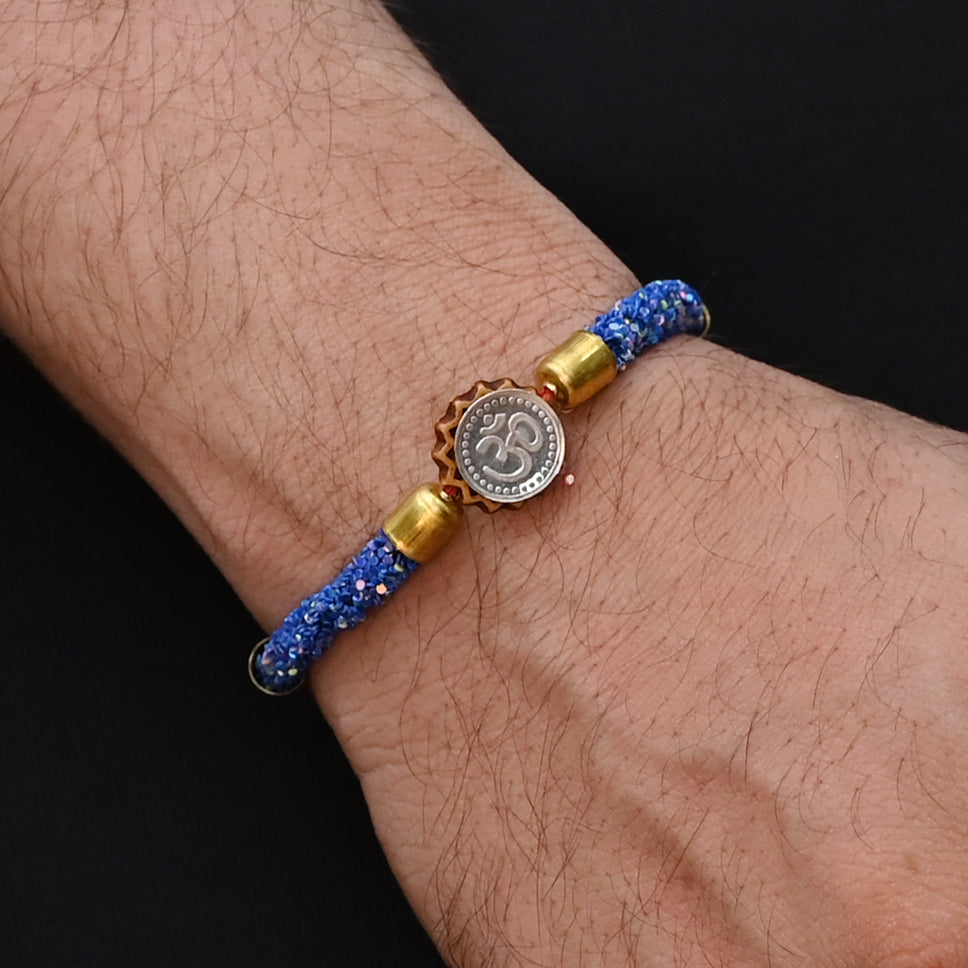 Elegant Rakhi with a silver Om symbol and blue flat circular beads, ideal for boys.