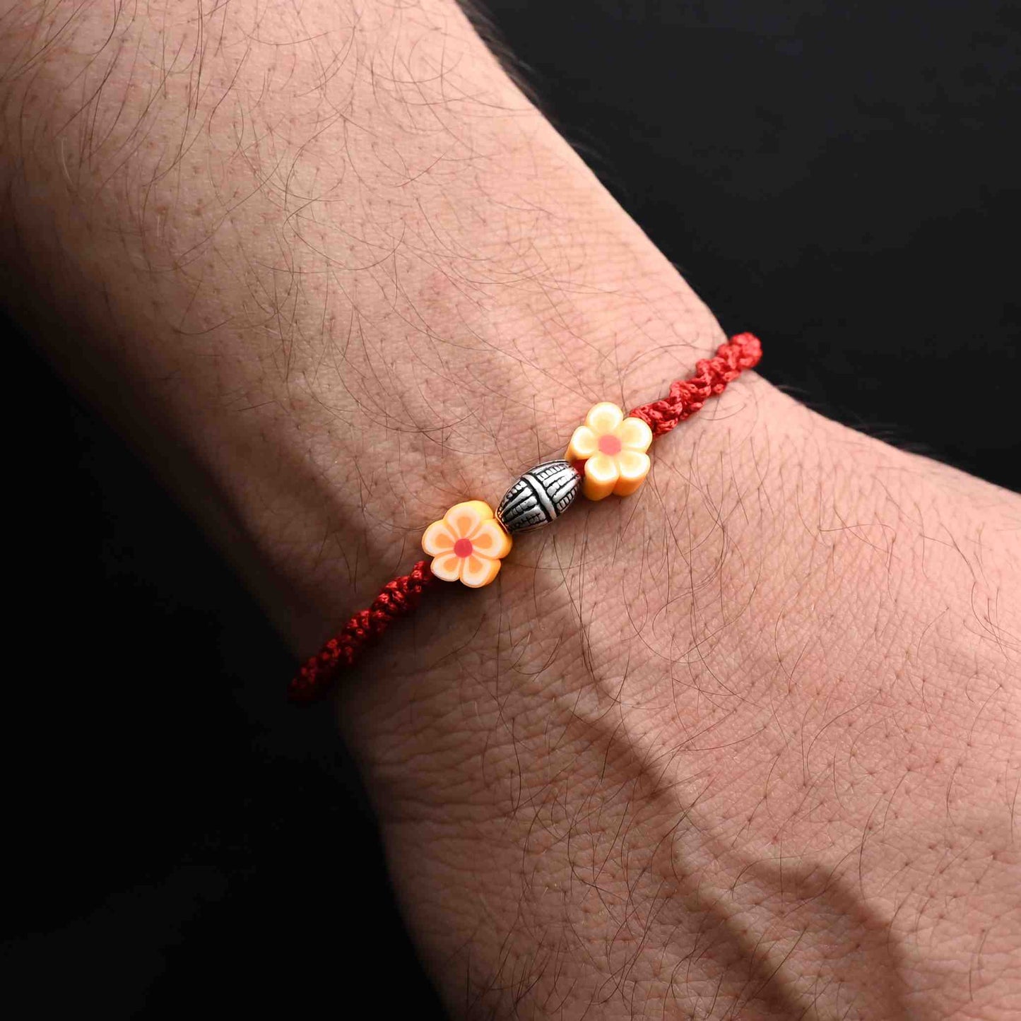 Elegant Rakhi with a sterling silver orange flower, ideal for boys.