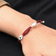 Silver bracelet featuring vibrant red beads and a protective evil eye charm