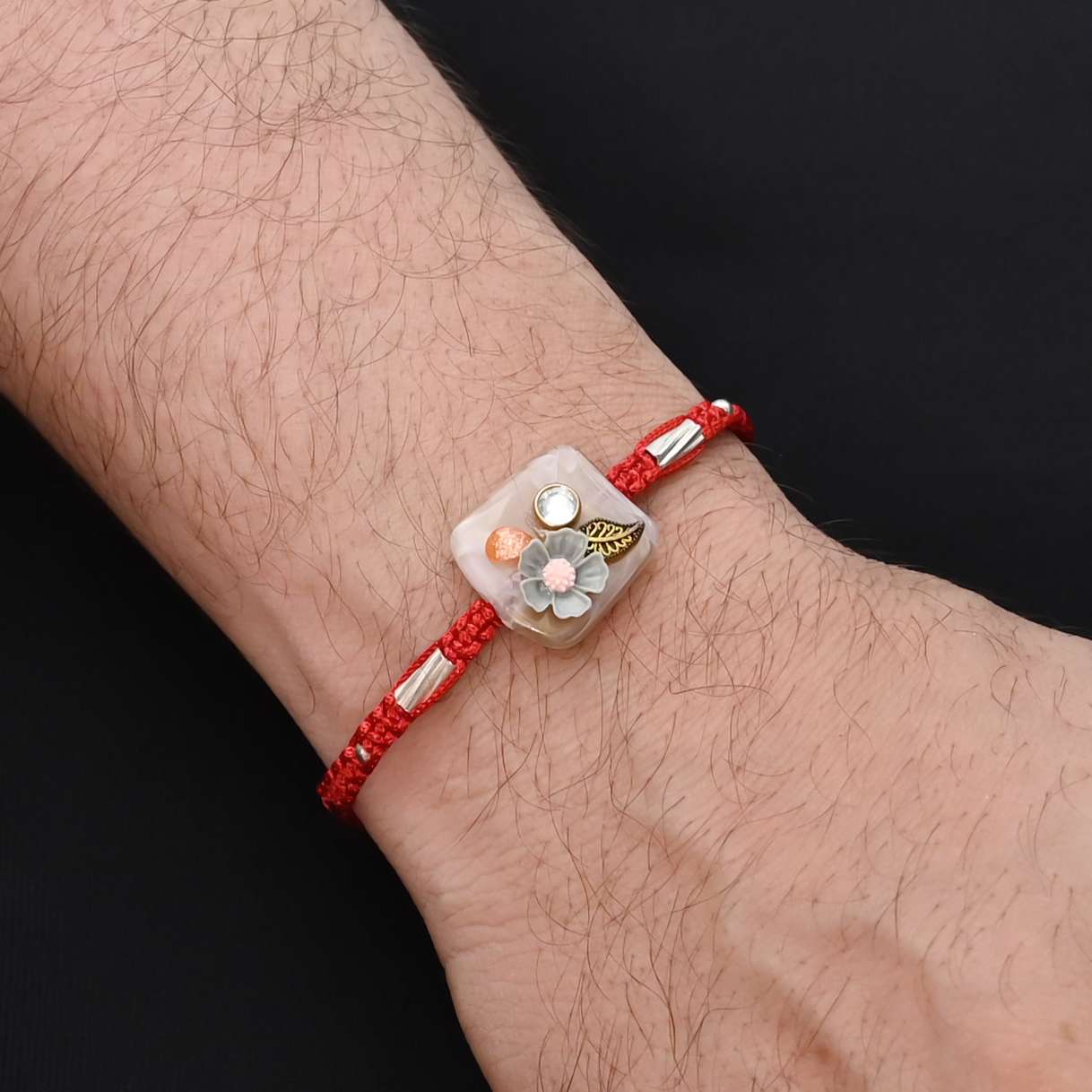 Elegant Rakhi with a silver grey flower and leaf design, ideal for boys.