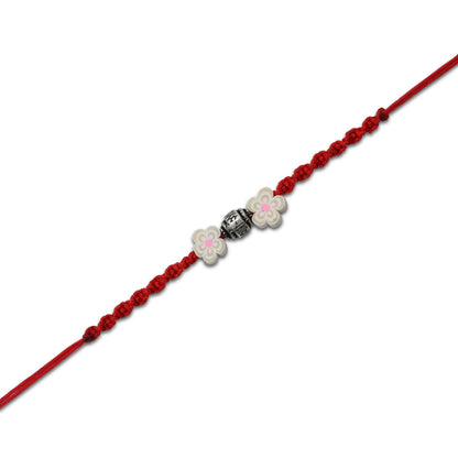 Boys' Rakhi featuring a silver bead centerpiece and two elegant cream-colored flowers.