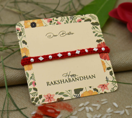 Silver Rakhi with small flower design beads and a red thread, perfect for boys.