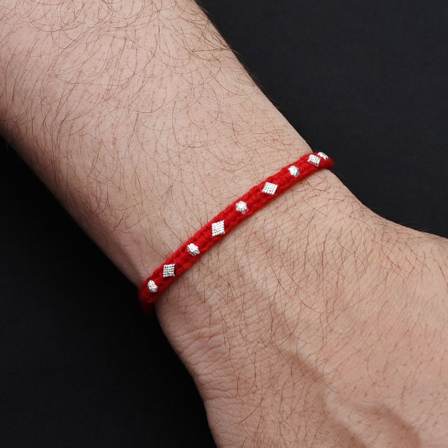 Elegant Rakhi with silver beads in a small flower design and red thread, ideal for boys.
