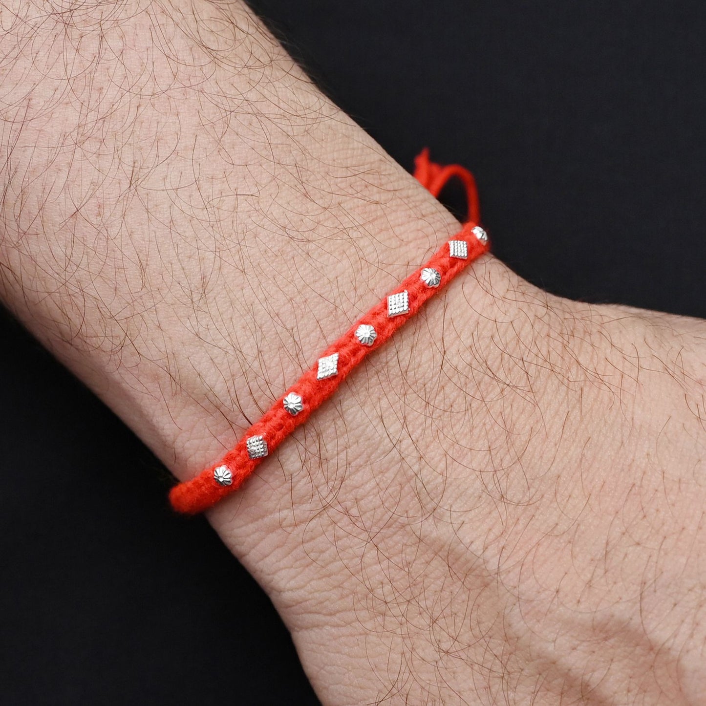 Elegant Rakhi with a silver small flower motif and orange thread, ideal for boys