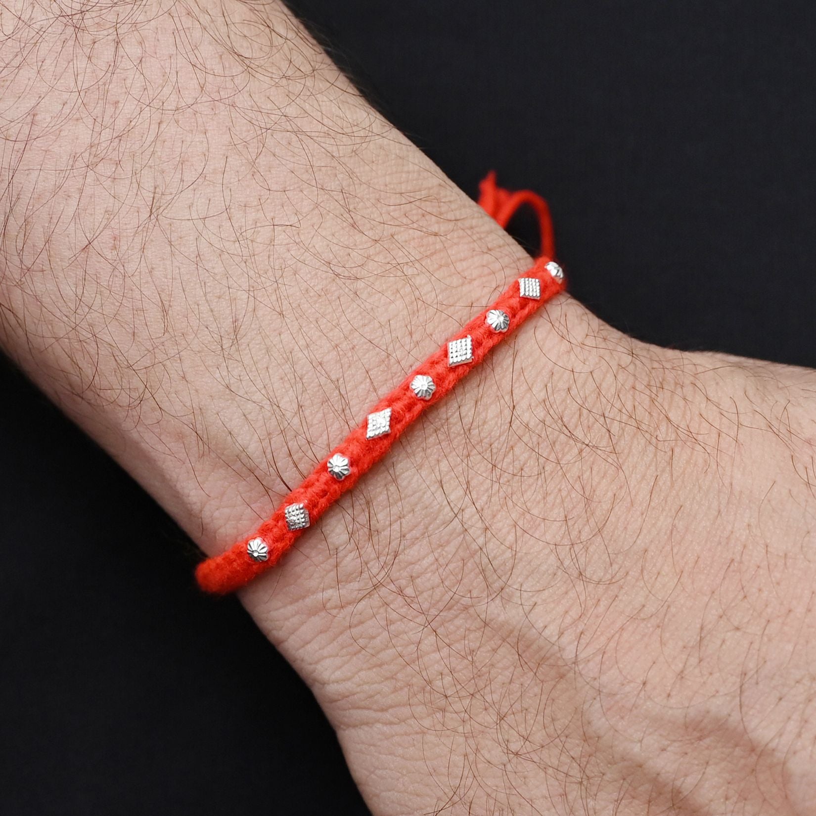 Elegant Rakhi with a silver small flower motif and orange thread, ideal for boys