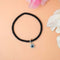 A stylish black bracelet featuring a silver evil eye charm
